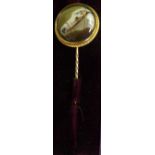A mid Victorian gold coloured metal stick pin with a painted enamel tablet,