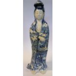An early 20thC Chinese porcelain standing figure, Guan Yin, holding a basket of fish,