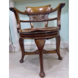 An early 20thC mahogany framed desk chair, having a round back with a scrolled crest,