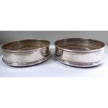 A pair of silver wine coasters with turned mahogany bases indistinct makers marks London 1978