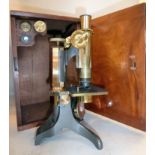 An early 20thC black enamelled and lacquered brass microscope with two rotating lenses,
