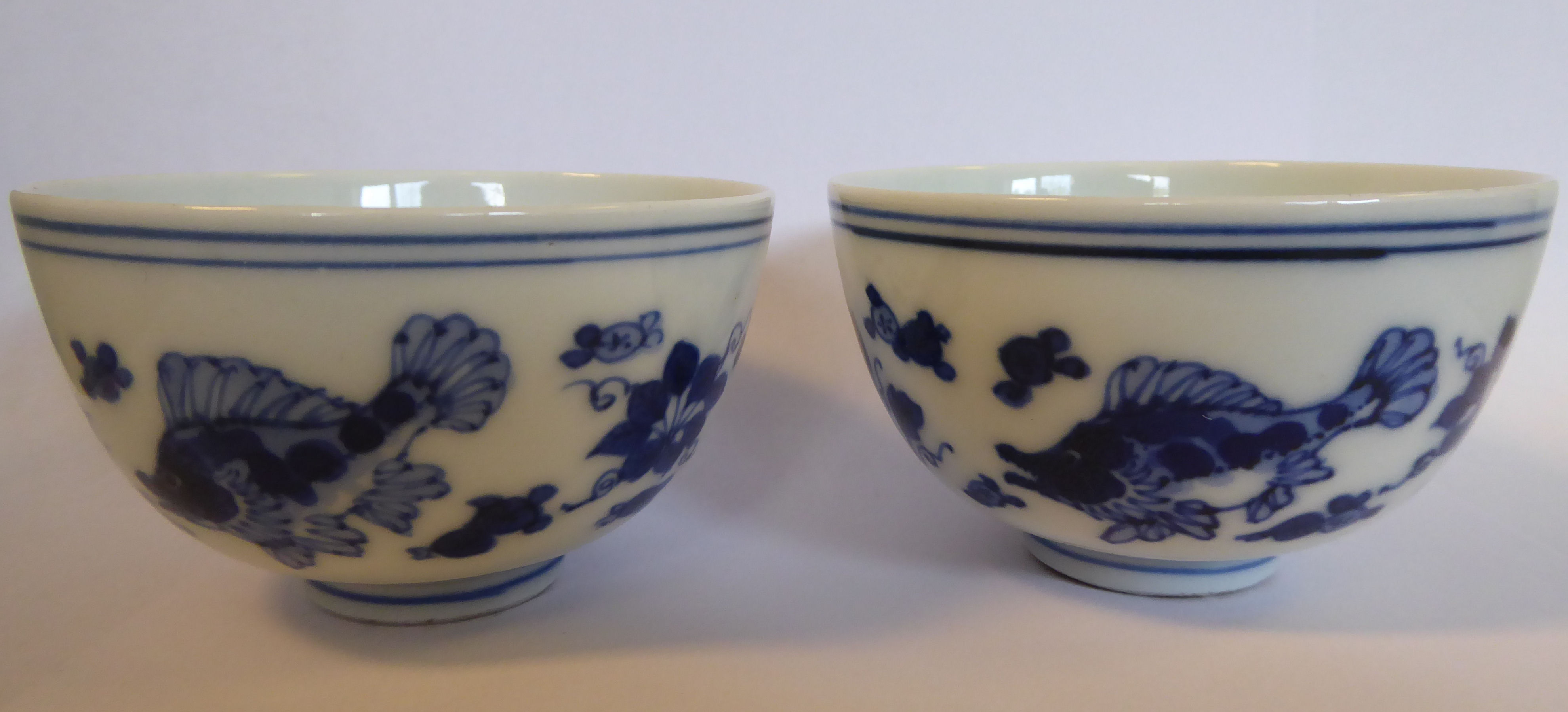 A pair of late 19th/early 20thC Japanese porcelain tea bowls, decorated in blue and white with carp,