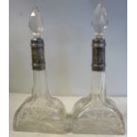 A pair of facet and diamond cut glass dressing table bottles of demi-lune design with long narrow