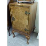 A mid 20thC figured walnut bedside cabinet, having a single door with cast metal butterfly hinges,