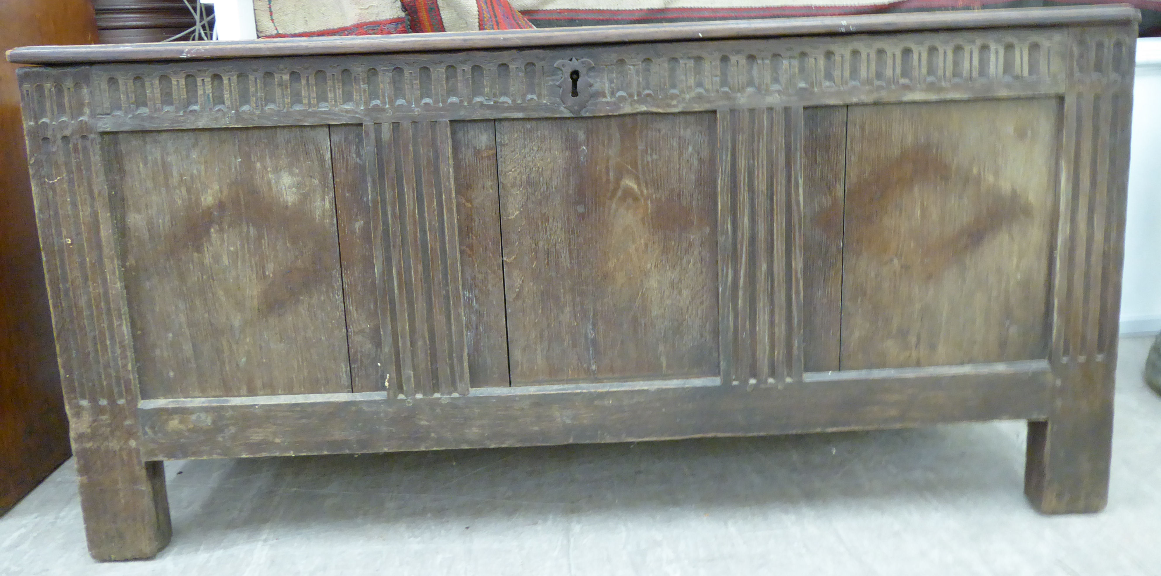 An early 18thC stained pine coffer with straight sides a hinged lid, over a panelled front,