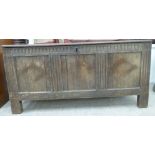 An early 18thC stained pine coffer with straight sides a hinged lid, over a panelled front,