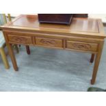 A modern Chinese hardwood panelled and mitred side table with three carved in-line drawers,