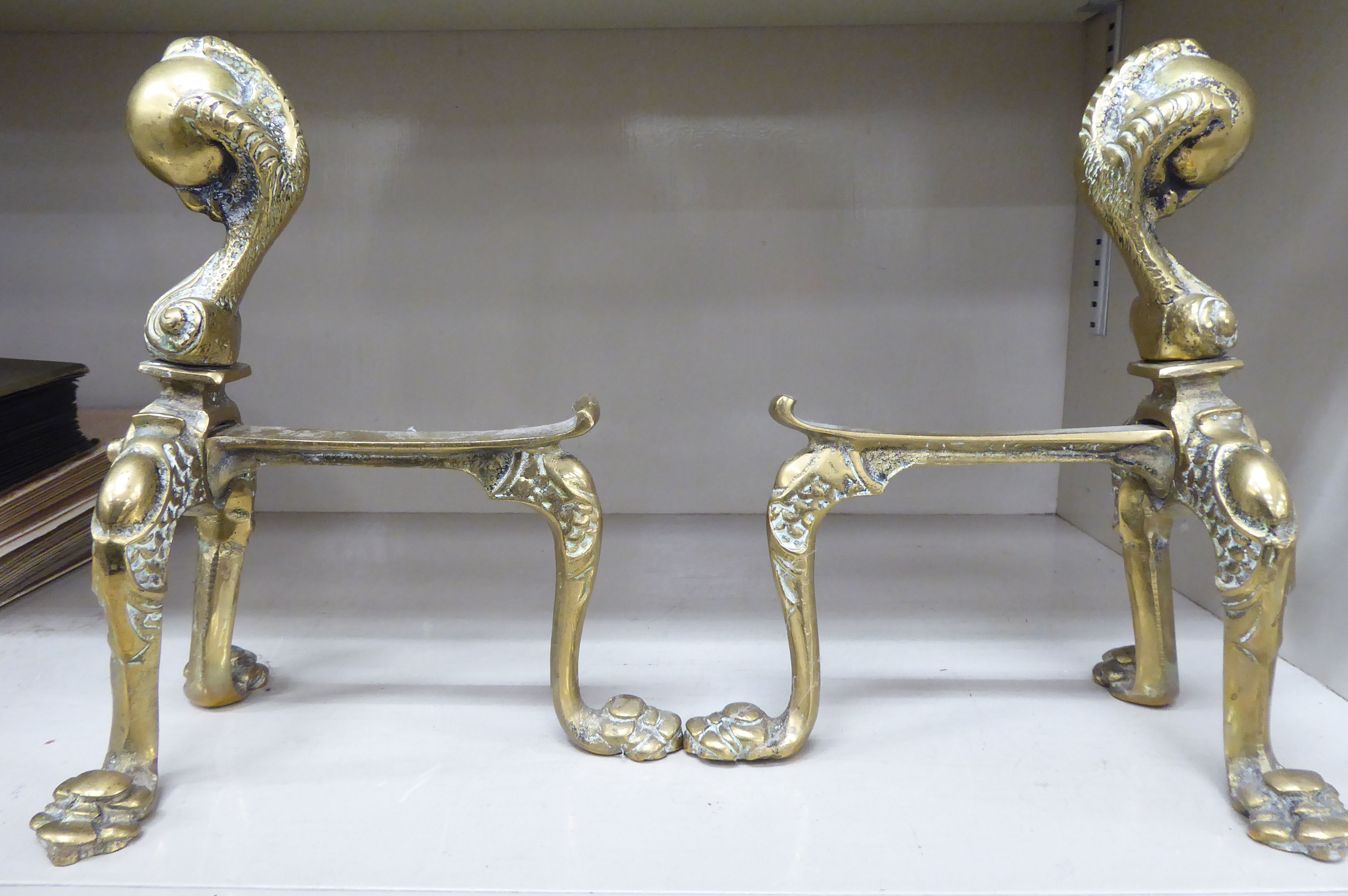 A pair of early 20thC brass fire dogs with a talon and ball finials and cabriole legs 9''h