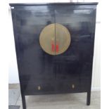 A mid 20thC Chinese black lacquered hardwood marriage cabinet, the pair of doors with a two part,