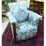 An Edwardian mahogany framed easy chair, upholstered in gold coloured and blue floral fabric,
