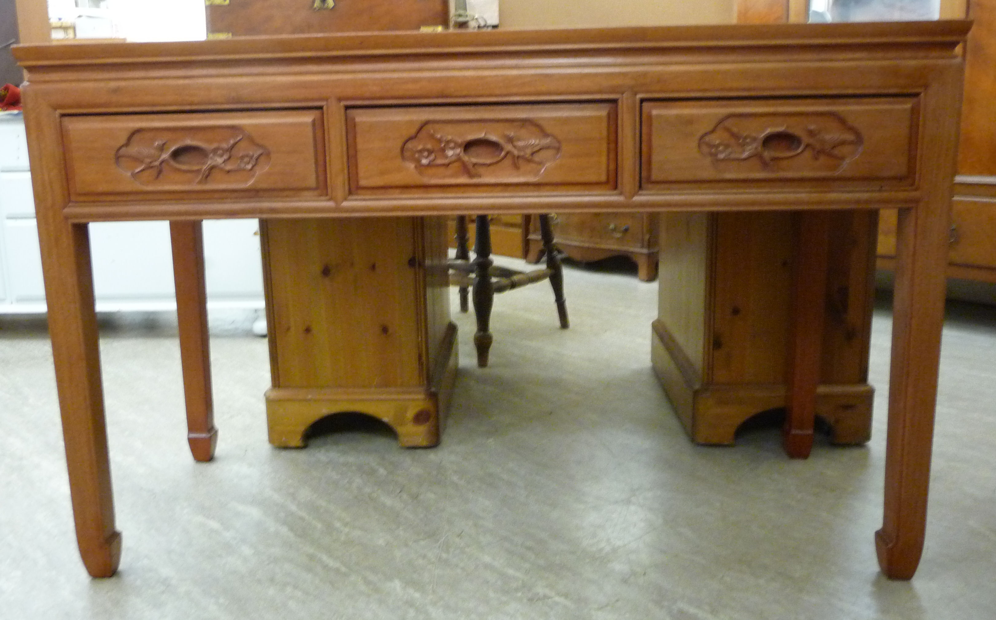 A modern Chinese hardwood panelled and mitred side table with three carved in-line drawers,