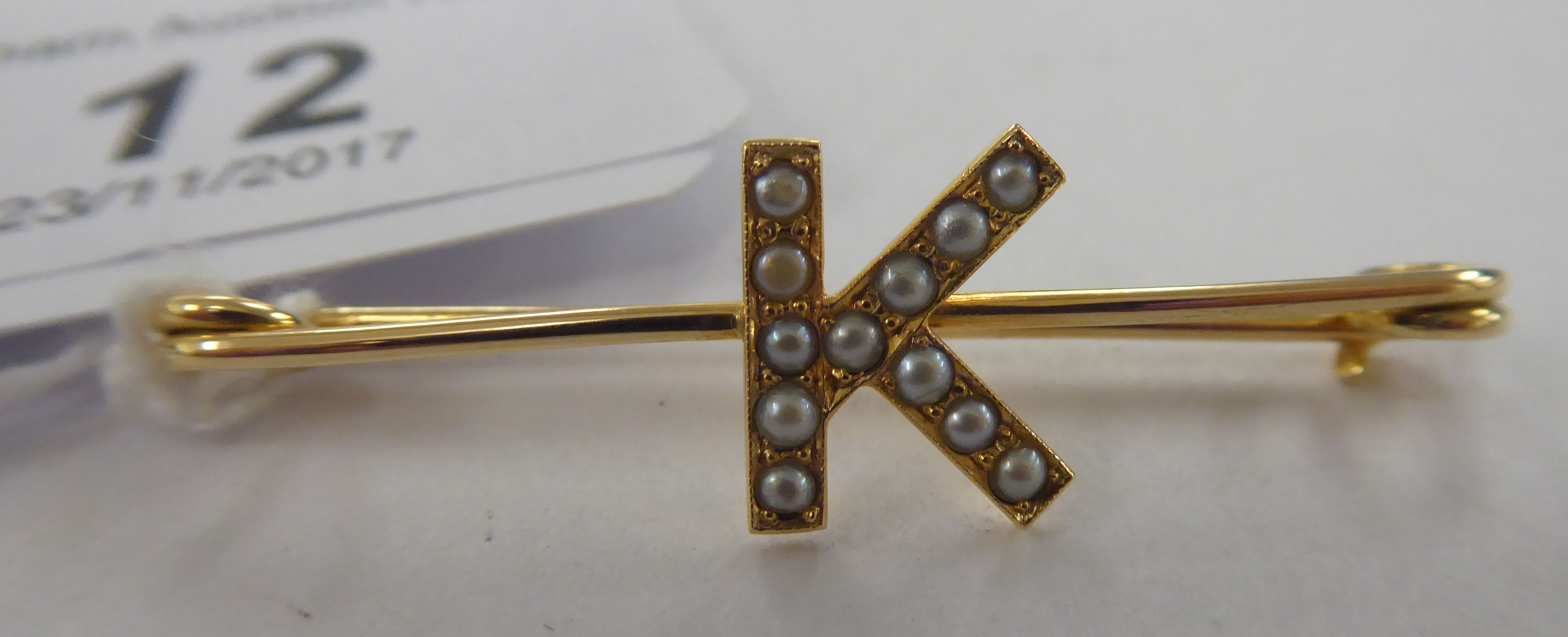 A gold coloured metal pin brooch,