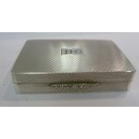 A silver pill box of rectangular form with engine turned decoration and a flush fitting hinged lid