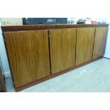 A 1970s/80s exotic hardwood finished sideboard with four in-line doors,