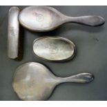 A three piece silver backed dressing table set comprising a hand mirror,