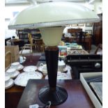 An Art Deco cream coloured enamelled steel and brown Bakelite table lamp with copper trim and a