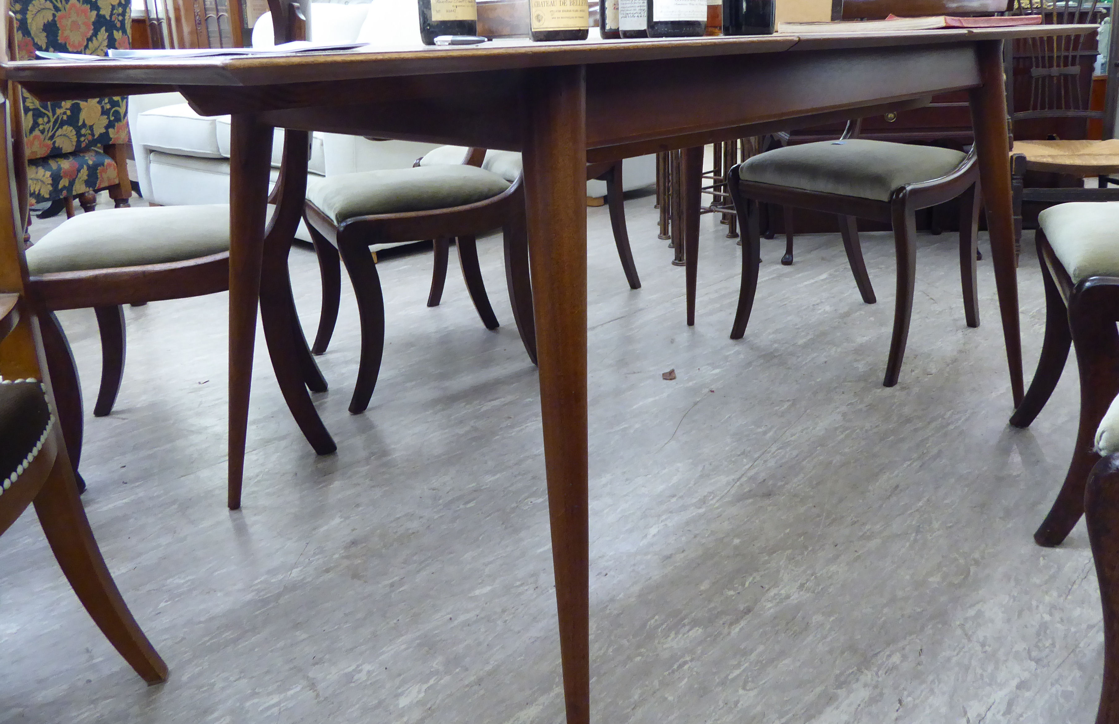 A 1970s teak extending dining table, the top with a moulded edge,