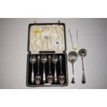 A set of six silver teaspoons in fitted case; a pair of sugar tongs; a sugar sifting spoon;