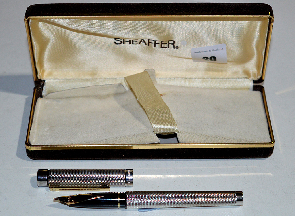 A Sheaffer fountain pen, in silver plated chequer cut case, fitted 14ct. yellow gold nib, boxed.