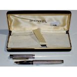 A Sheaffer fountain pen, in silver plated chequer cut case, fitted 14ct. yellow gold nib, boxed.