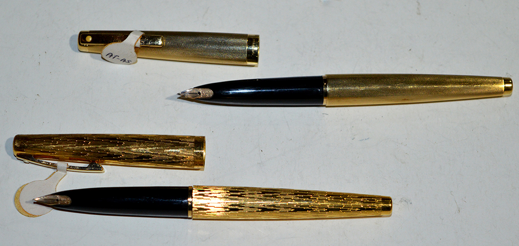 Two Sheaffer fountain pens in gold plated cases, one with zigzag design, the other plain,