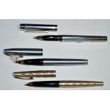 Three Sheaffer fountain pens, one in silver coloured case with gold decorated wave design,
