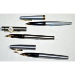 Three steel cased Sheaffer fountain pens, one with gold plated feather scroll collar,