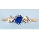 A sapphire and diamond ring, the circular facet cut sapphire flanked by old cut diamonds,