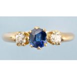 A sapphire and diamond ring, the central circular facet cut sapphire flanked by old cut diamonds,