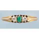 An emerald and diamond ring, the central oval facet cut emerald flanked by old cut diamonds,