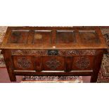 An 18th Century oak coffer, the plain panel top above carved frieze and front panels,