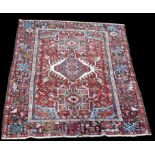 A Heriz rug, with triple medallion, on red ground with flowerheads, 188 x 144cms (74 x 56 1/2in.).