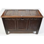 An 18th Century oak coffer, the plain panel top above carved leaf pattern frieze,