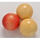 Three 19th Century ivory billiard balls, two white and one stained red, each 2in. (5cms) diameter.