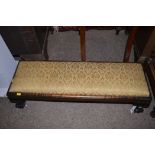 A stained wood rectangular footstool, raised on claw and ball feet,