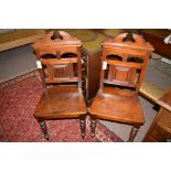 A pair of Victorian walnut hall chairs, raised on turned tapering legs.