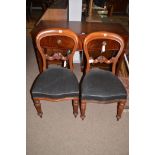 A pair of Victorian walnut balloon back dining chairs with carved mid rails,