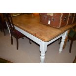 A stripped pine top white painted kitchen table, raised on turned legs.