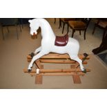 An early 20th Century rocking horse, later red leatherette saddle, on pine base.