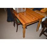 A stained pine kitchen table, fitted frieze drawer to both ends, raised on turned legs.