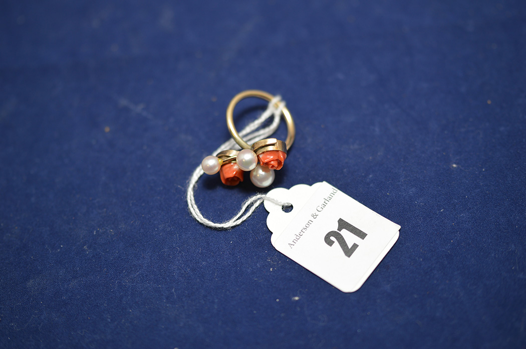 A yellow metal ring set with three cultured pearls and carved coral, in flowerhead pattern,