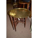 An Indian circular brass tray, raised on stained wood stand.