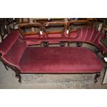 A Victorian ebonised chaise longue, upholstered in burgundy coloured velour,