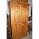 A modern pine wardrobe, raised on a plinth base, 108cms wide.