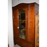 An Edwardian inlaid mahogany wardrobe, bevelled mirror door above single drawer, 127cms wide.