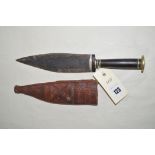 An early 20th Century North African dagger, wooden and brass grip in embossed leather scabbard.