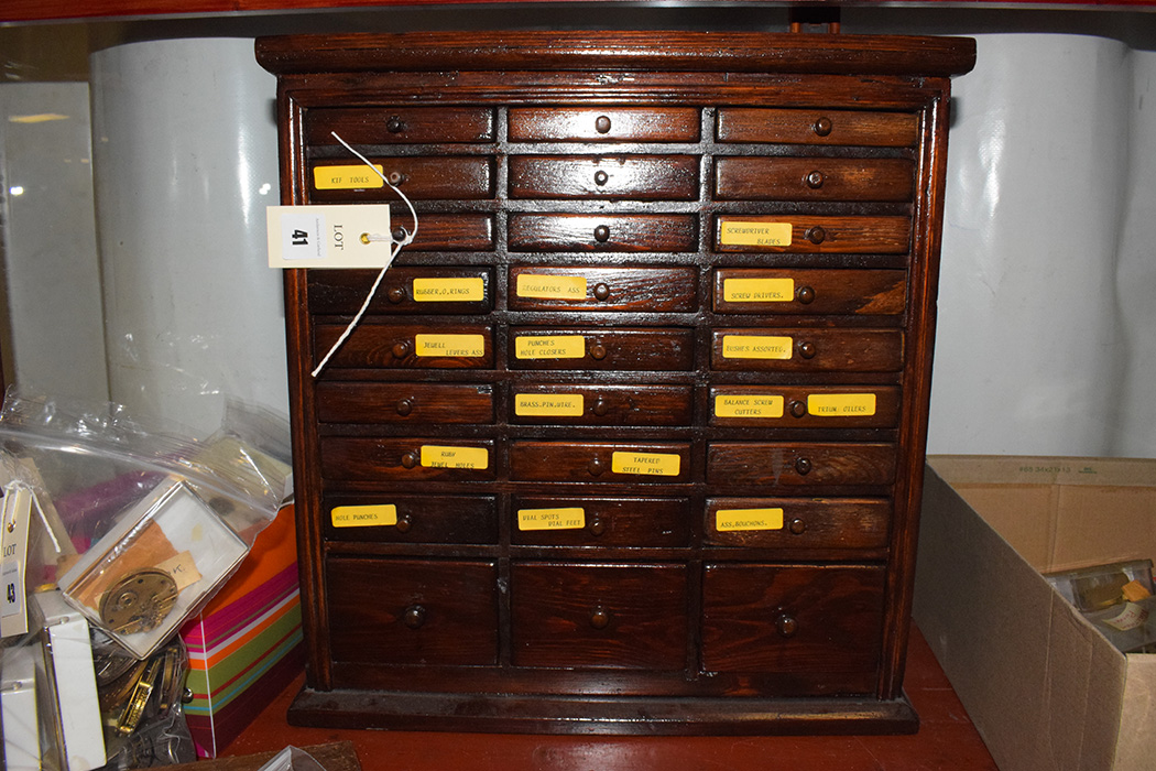 A watchmakers cabinet, containing various pocket watch accessories, to include: screwdriver blades,