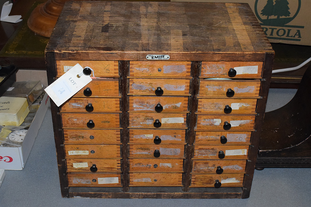 A watchmakers cabinet containing a selection of tools and parts.