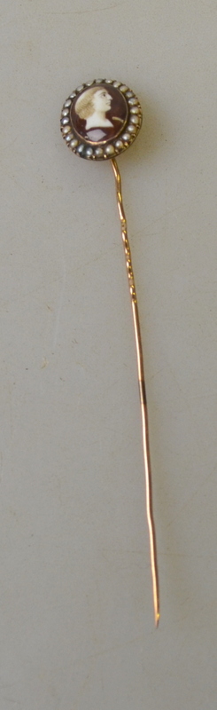 A yellow metal stick pin with enamel cla