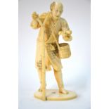 A Japanese stained ivory okimono of a standing bird catcher,